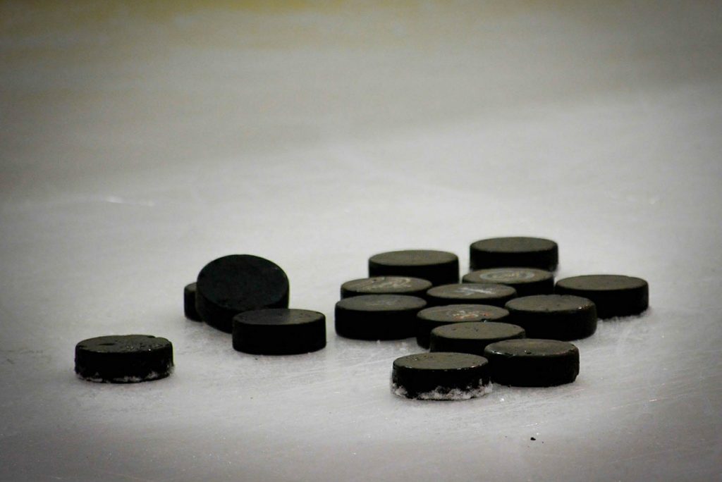 Ishockeypuckar som ligger på isen.